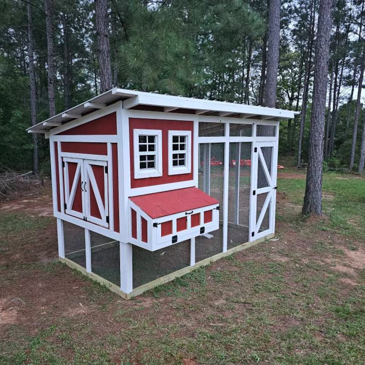 Finished red board-and-batten chicken coop with run
